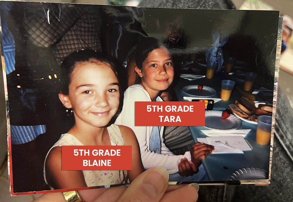 Photo of a printed photo from the '90s of Blaine and Tara at a lunch table together in 5th grade