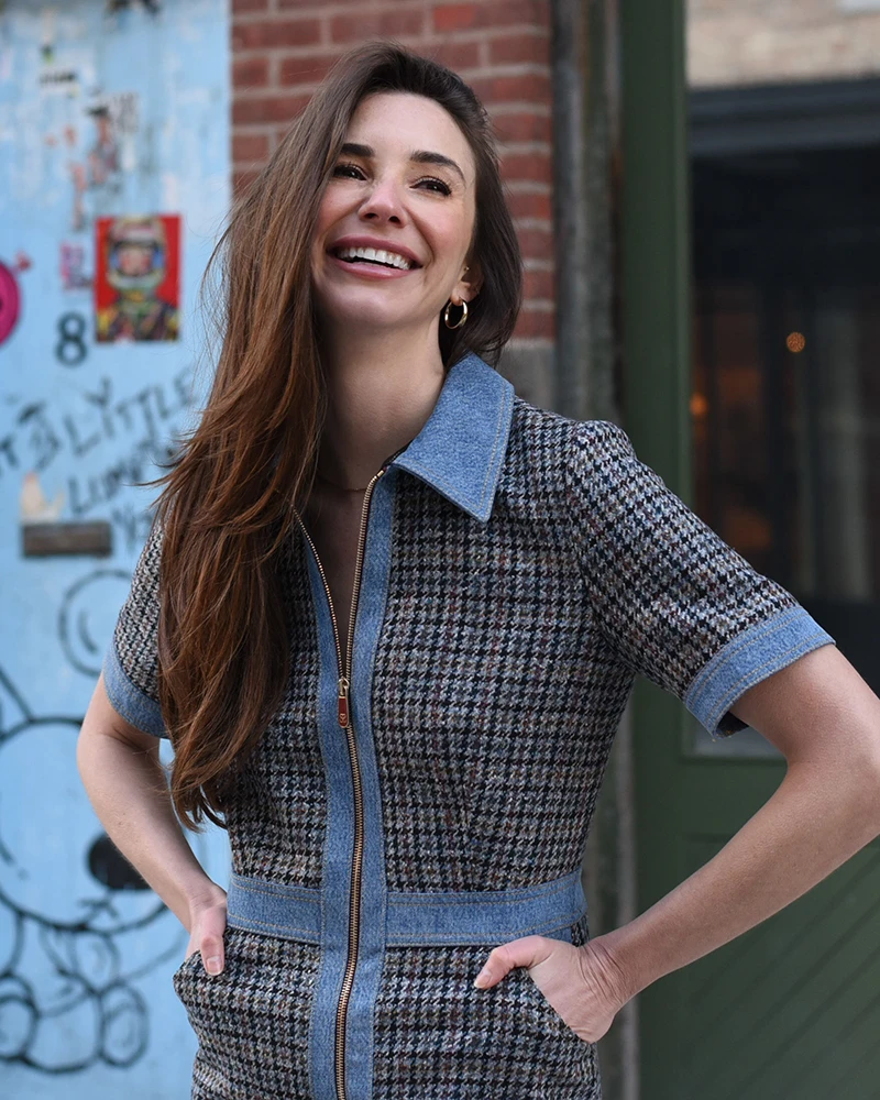 Photo of Blaine smiling, in a blue dress, on a street in the West Village