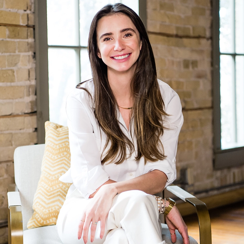 Photo of Blaine in a white outfit in a loft-like building, smiling